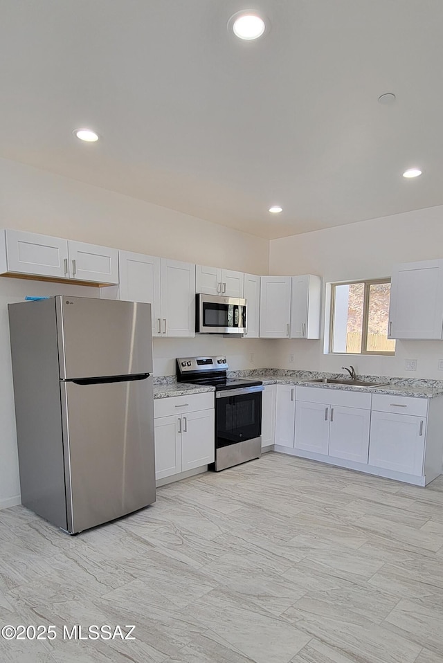 kitchen featuring white cabinets, light stone countertops, stainless steel appliances, and recessed lighting