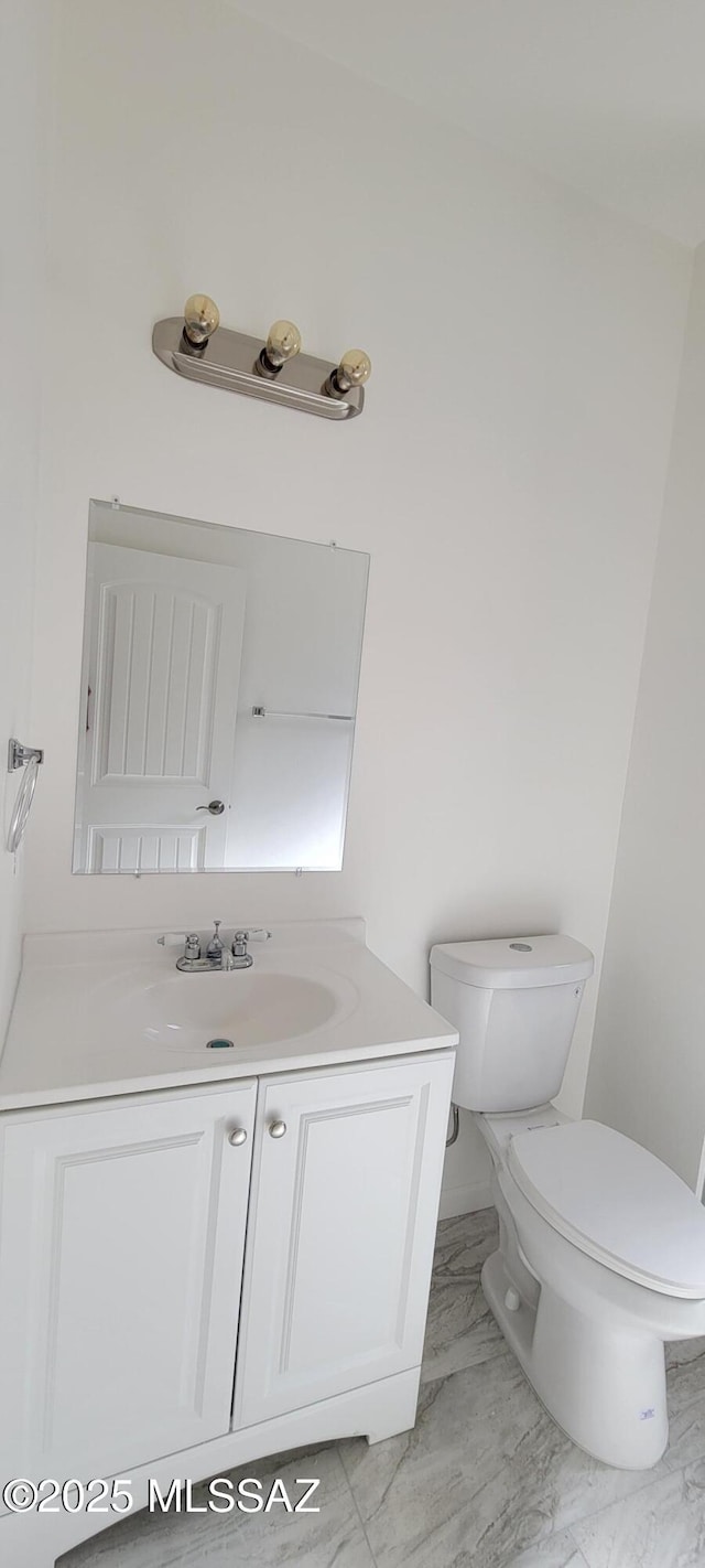 bathroom with toilet, marble finish floor, and vanity