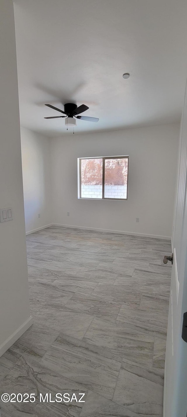 empty room featuring ceiling fan and baseboards