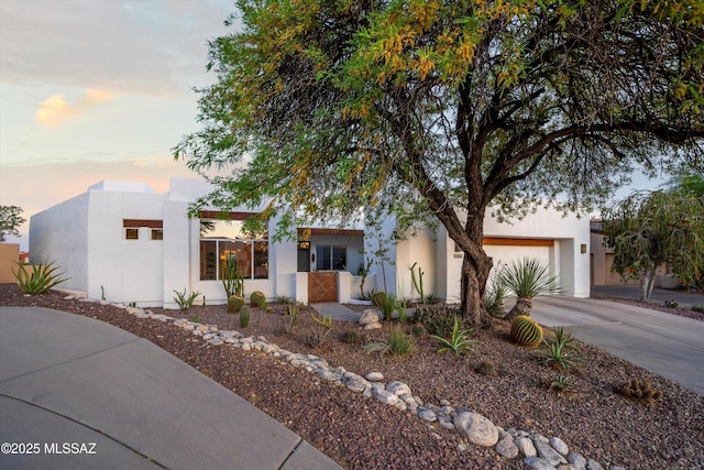 view of front of house featuring an attached garage, concrete driveway, and stucco siding