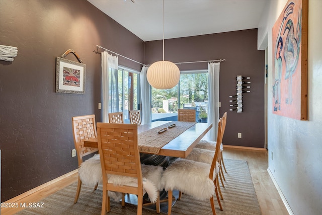 dining room with baseboards, a textured wall, and wood finished floors