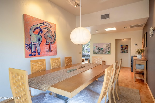 dining space with track lighting, parquet floors, and visible vents