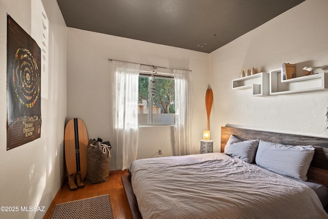 bedroom featuring arched walkways and wood finished floors