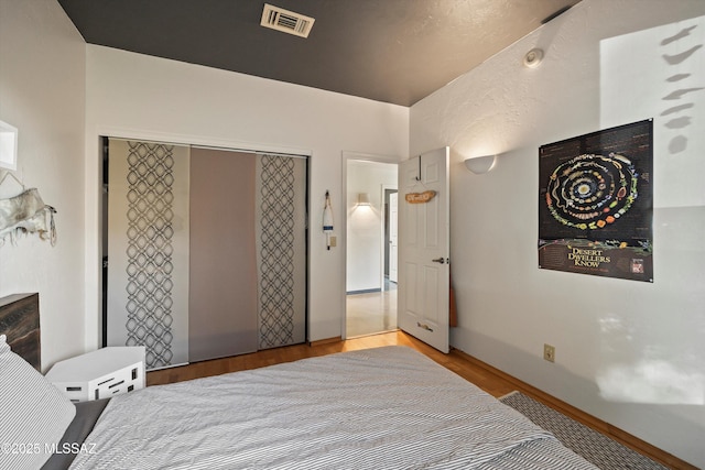 bedroom featuring visible vents, wood finished floors, and a closet
