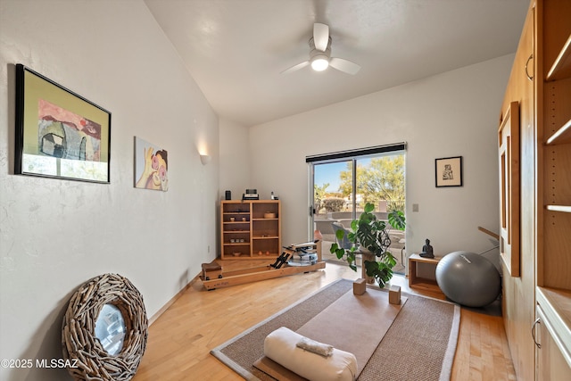 workout room with light wood-style floors, ceiling fan, and vaulted ceiling