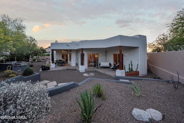 back of property at dusk with a patio, fence, and stucco siding
