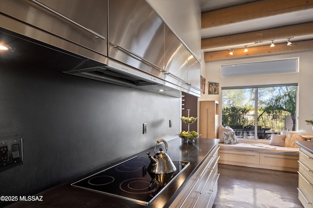 kitchen featuring a high ceiling, black electric stovetop, rail lighting, extractor fan, and finished concrete floors