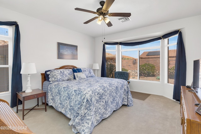 bedroom featuring baseboards, visible vents, a ceiling fan, and light carpet