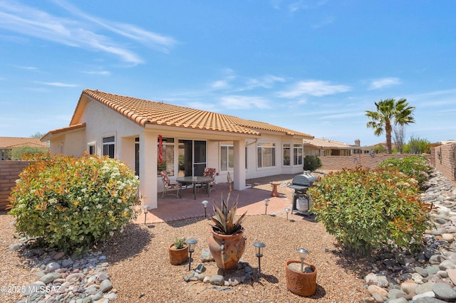rear view of property with a fenced backyard, stucco siding, a tile roof, and a patio area