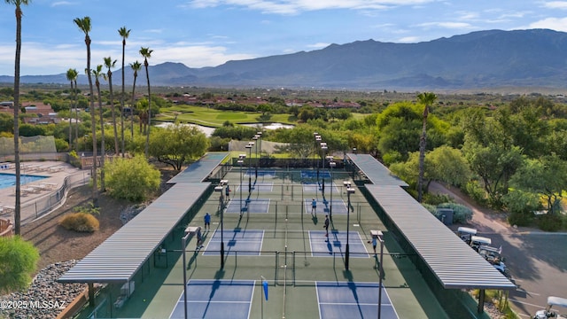 view of property's community with fence, golf course view, a mountain view, and a tennis court