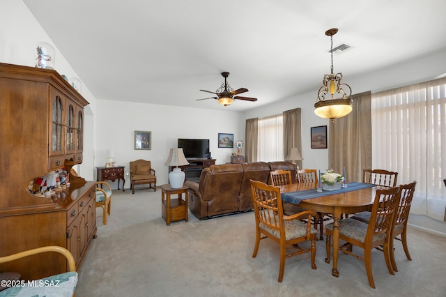 dining space with ceiling fan, light carpet, and visible vents