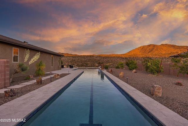 35605 S Overlook Dr, Saddlebrooke, AZ 85739 - pool at dusk featuring a mountain view, an outdoor pool, a fenced backyard, and a patio area