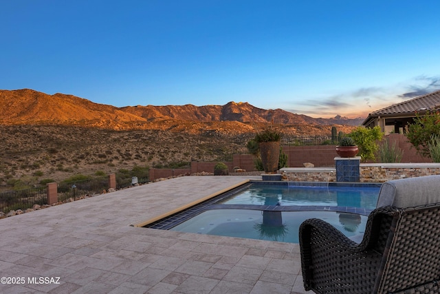 35605 S Overlook Dr, Saddlebrooke, AZ 85739 - pool at dusk featuring a mountain view, a fenced backyard, a pool with connected hot tub, and a patio area