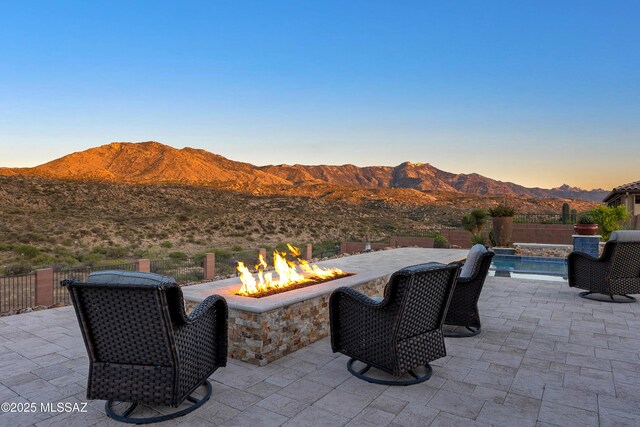35605 S Overlook Dr, Saddlebrooke, AZ 85739 - patio terrace at dusk with an outdoor fire pit, a mountain view, a fenced backyard, and a fenced in pool