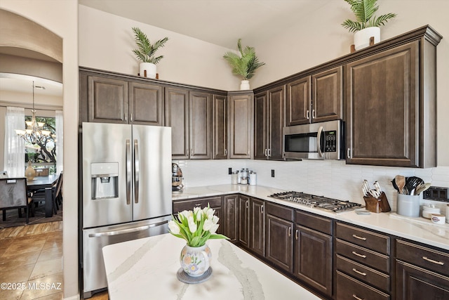 kitchen featuring backsplash, an inviting chandelier, dark brown cabinets, and stainless steel appliances