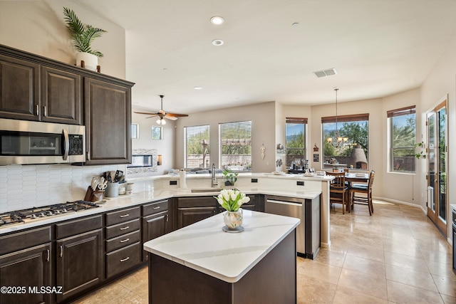 kitchen with a peninsula, dark brown cabinets, appliances with stainless steel finishes, and recessed lighting