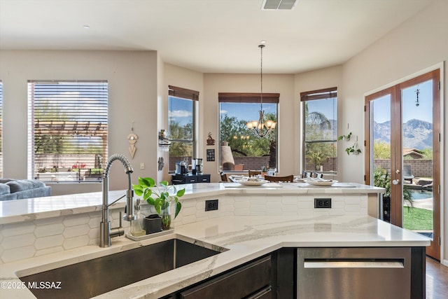 kitchen featuring dishwasher, an inviting chandelier, light stone countertops, and a sink