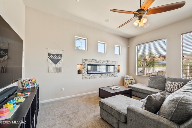living room featuring a wealth of natural light, a ceiling fan, baseboards, and light colored carpet