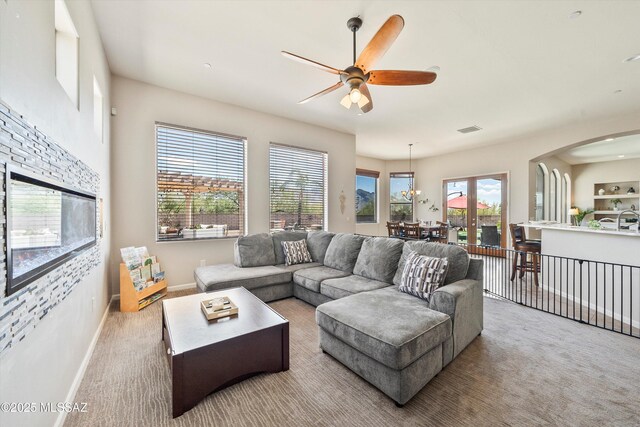 living area with visible vents, arched walkways, baseboards, carpet flooring, and ceiling fan