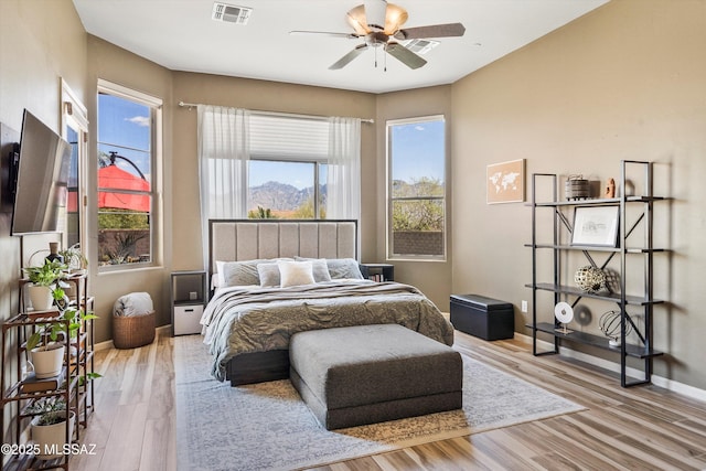 bedroom featuring baseboards, wood finished floors, visible vents, and ceiling fan