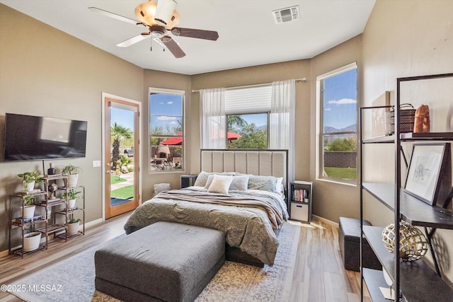 bedroom featuring a ceiling fan, wood finished floors, baseboards, access to outside, and visible vents