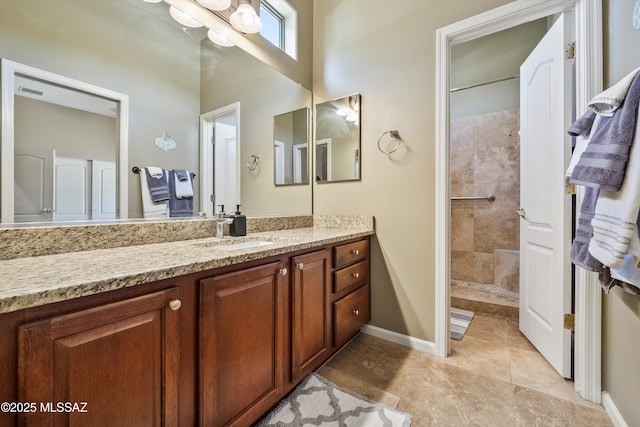 bathroom with tile patterned flooring, visible vents, vanity, baseboards, and tiled shower