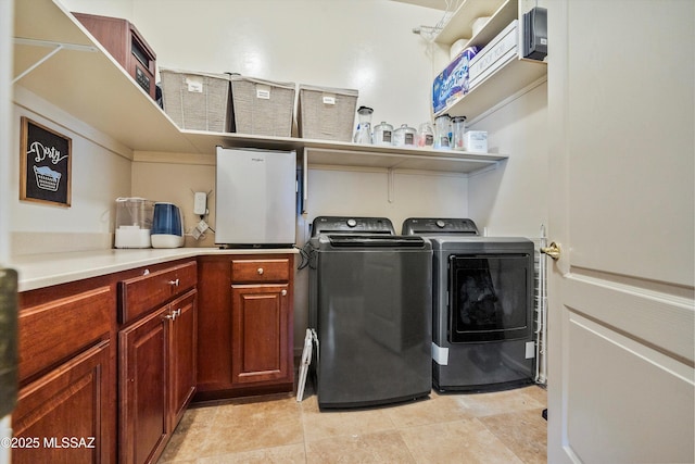 laundry area with cabinet space, washing machine and clothes dryer, and light tile patterned floors