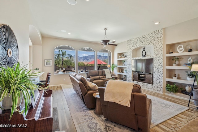 living room featuring a ceiling fan, hardwood / wood-style flooring, built in shelves, baseboards, and recessed lighting