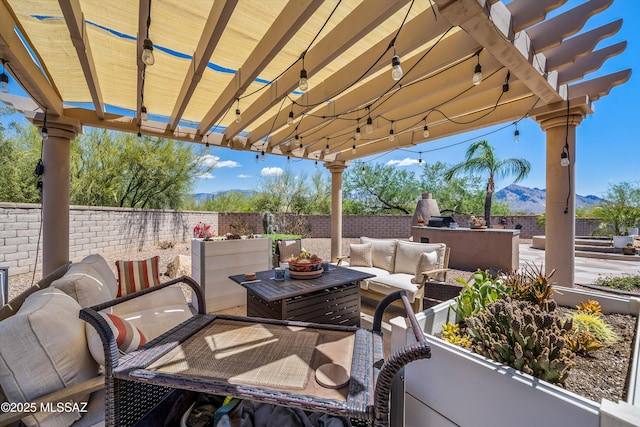 view of patio / terrace with an outdoor kitchen, a mountain view, a fenced backyard, and an outdoor living space