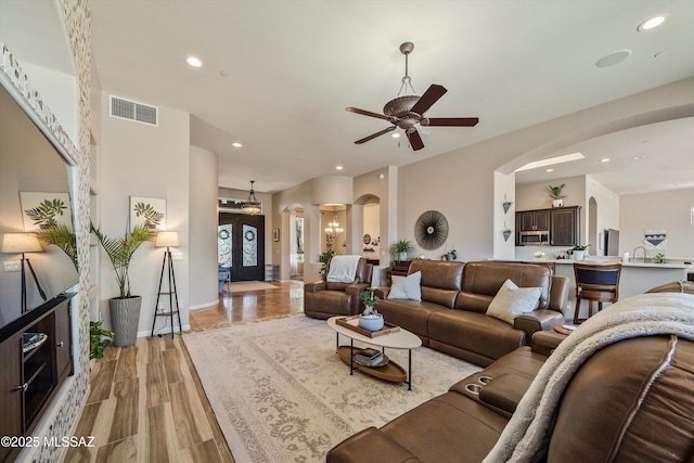 living area with a ceiling fan, visible vents, arched walkways, and recessed lighting