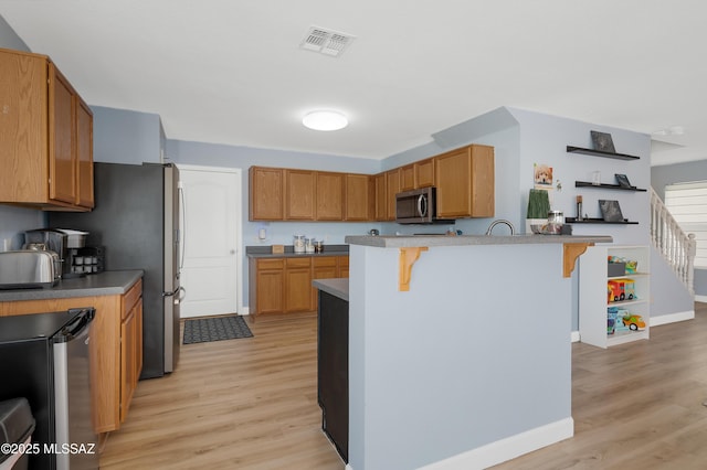 1985 S Mcconnell Dr, Tucson, AZ 85710 - kitchen featuring visible vents, baseboards, stainless steel microwave, light wood finished floors, and a breakfast bar area