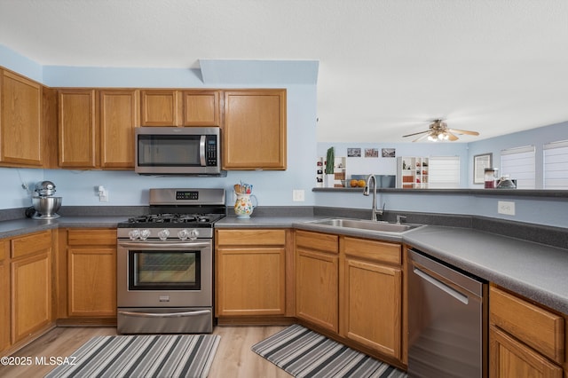 1985 S Mcconnell Dr, Tucson, AZ 85710 - kitchen with appliances with stainless steel finishes, light wood finished floors, a sink, and dark countertops