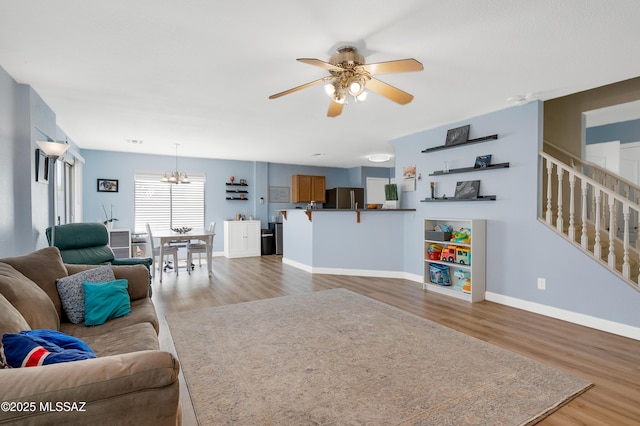 1985 S Mcconnell Dr, Tucson, AZ 85710 - living room featuring ceiling fan with notable chandelier, wood finished floors, baseboards, and stairway