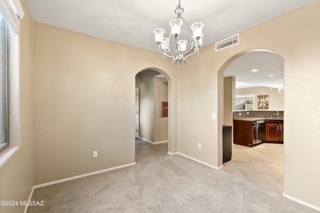 unfurnished room with arched walkways, light colored carpet, a sink, and visible vents