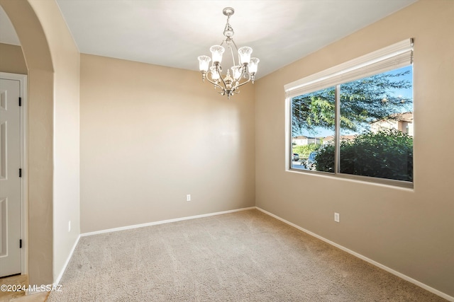 empty room featuring arched walkways, an inviting chandelier, baseboards, and carpet flooring