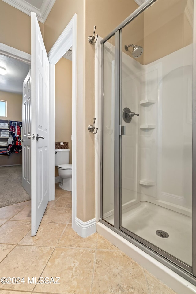 bathroom with a shower stall, tile patterned floors, ornamental molding, and toilet