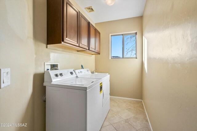 clothes washing area with visible vents, baseboards, light tile patterned floors, cabinet space, and washer and clothes dryer