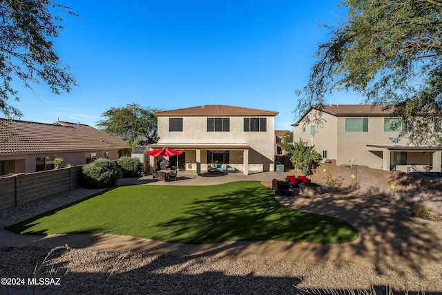 rear view of house with a patio, stucco siding, a fenced backyard, and a lawn