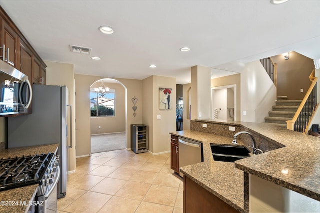 kitchen featuring dark stone counters, visible vents, appliances with stainless steel finishes, a sink, and beverage cooler
