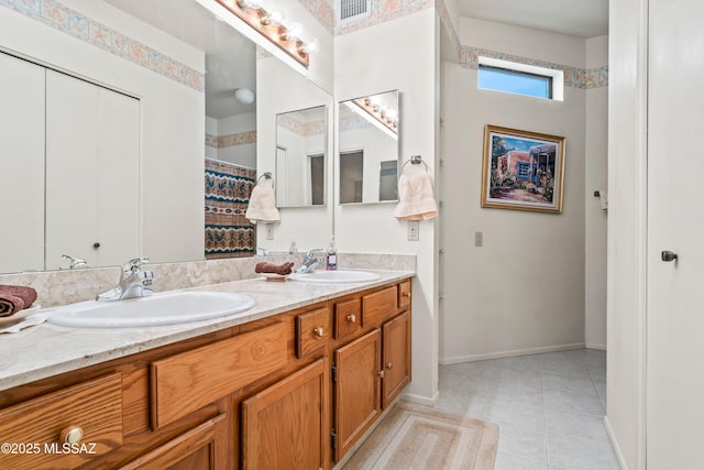 full bath with tile patterned floors, double vanity, baseboards, and a sink