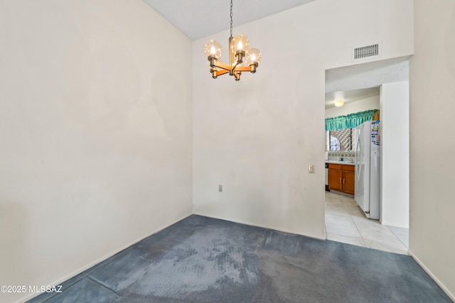 empty room featuring visible vents, light colored carpet, a notable chandelier, and light tile patterned floors