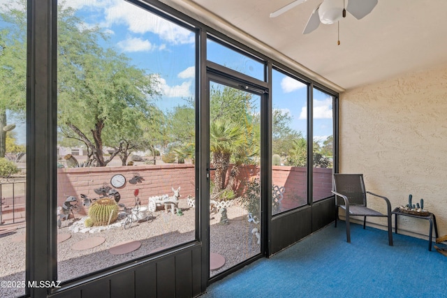 unfurnished sunroom featuring a textured wall, ceiling fan, and carpet floors