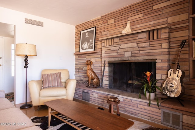 living room featuring a stone fireplace and visible vents