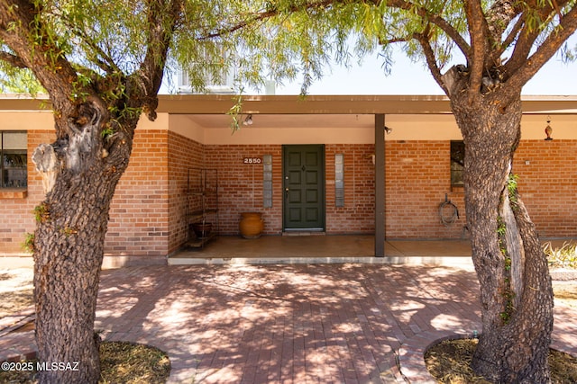 back of house with covered porch and brick siding