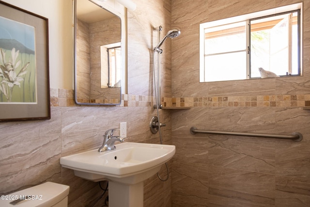 bathroom featuring toilet, tile walls, and a tile shower