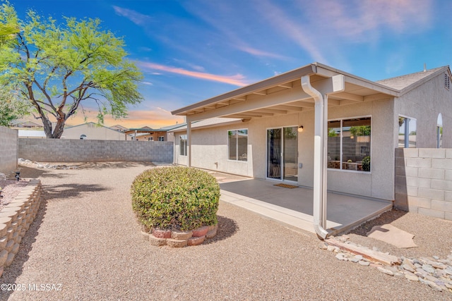 8972 E Mcmurray Pl, Tucson, AZ 85730 - back of property at dusk featuring stucco siding, a patio area, and a fenced backyard