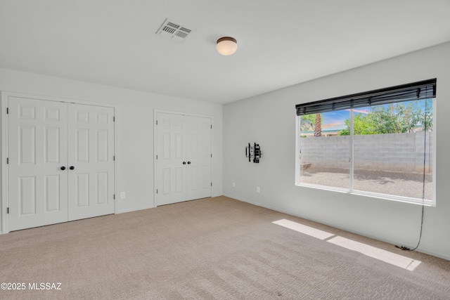 8972 E Mcmurray Pl, Tucson, AZ 85730 - unfurnished bedroom featuring two closets, carpet flooring, and baseboards