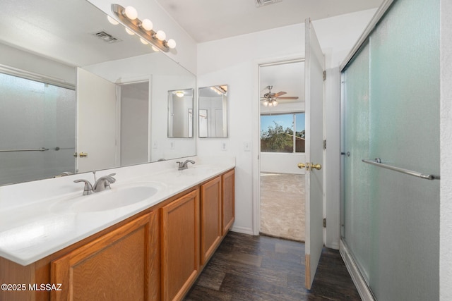 bathroom featuring a sink, double vanity, wood finished floors, and visible vents