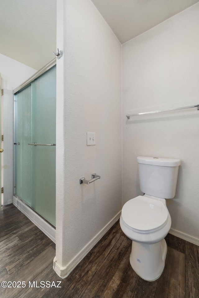 bathroom featuring baseboards, a stall shower, toilet, and wood finished floors