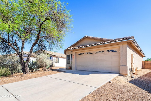 ranch-style home featuring a garage, stucco siding, driveway, and a tiled roof